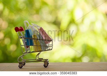 Online Shopping, E-commerce Concept: Paper Shopping Bags In A Trolley Or Shopping Cart  In The Natur