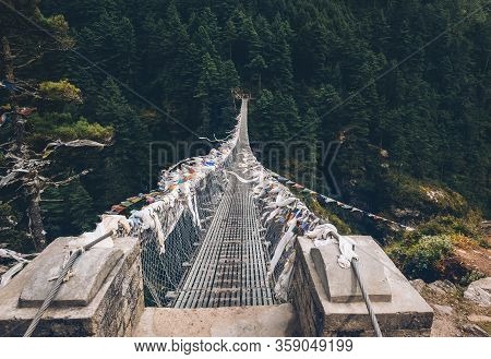 Suspension Bridge Decorated With Multicolored Tibetan Prayer Flags Hinged Over Gorge. Everest Base C