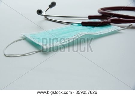 A Hygienic Green Mask With Ear Loops And A Red Stethoscope On The Table