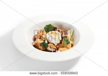 Salad in white bowl. Sliced octopus and fried potato. Served cut ingredients with mayonnaise, tomato spicy ajika and smoked pepper homemade sauce. Restaurant food portion in plate close up