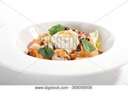 Salad in white bowl. Sliced octopus and fried potato. Served cut ingredients with mayonnaise, tomato spicy ajika and smoked pepper homemade sauce. Restaurant food portion in plate close up