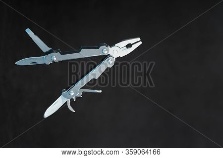 Multitool Is A Multi-functional Tool On A Black Background. The Concept Of An Expanded Multi-tool Wi