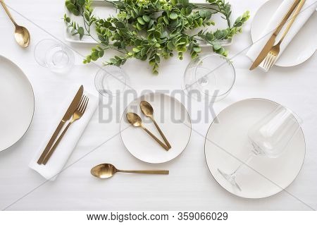 Tableware Background In White Gold Tone.white Plates, Gold Cutlery, Wine Glasses And Decorative Plan