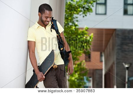 Unge sorte mænd ser ned med Skateboard og taske