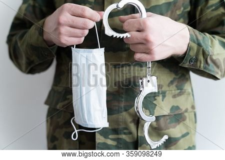 Police Officer With Face Mask And Handcuffs In Khaki Colored Uniform Stops, Arrest Criminal On The S