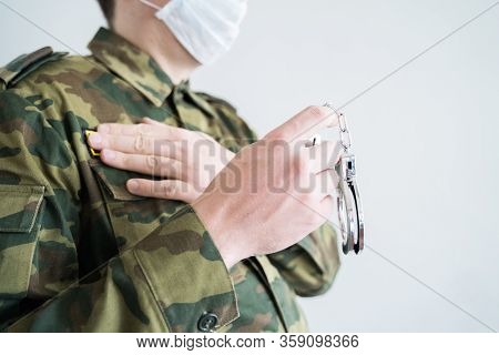 Police Officer With Face Mask And Handcuffs In Khaki Colored Uniform Stops, Arrest Criminal On The S