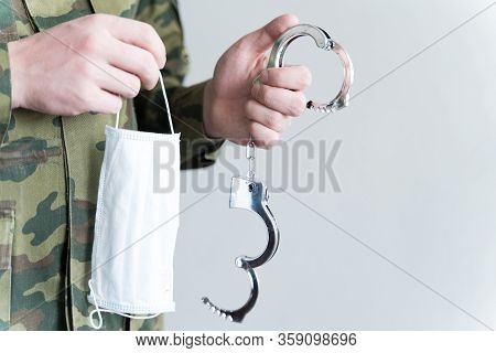 Police Officer With Face Mask And Handcuffs In Khaki Colored Uniform Stops, Arrest Criminal On The S