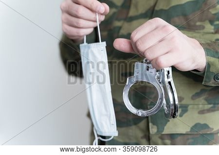 Police Officer With Face Mask And Handcuffs In Khaki Colored Uniform Stops, Arrest Criminal On The S