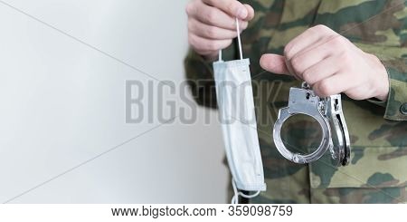 Police Officer With Face Mask And Handcuffs In Khaki Colored Uniform Stops, Arrest Criminal On The S
