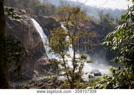 A Huge Waterfall Athirapally In Kerala, India. White Streams Of Water Of The Waterfall Break Into Sm