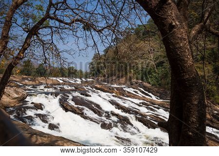 A Huge Waterfall Athirapally In Kerala, India. White Streams Of Water Of The Waterfall Break Into Sm