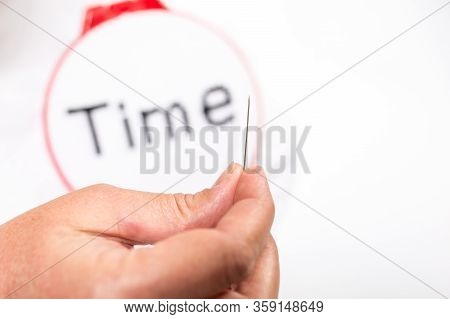 Difficult Painstaking Work. Hand With A Needle Close-up In Focus, With The Embroidered Word, Time In