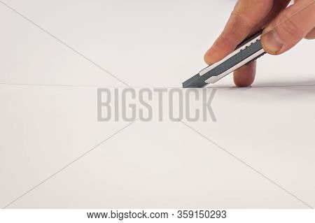 Close-up Of Hand With Skalpel. Worker Cut Paper In Printshop