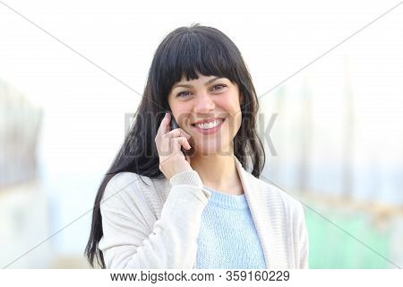 Front View Portrait Of A Happy Woman Talking On Smart Phone Looking At Camera Outdoor