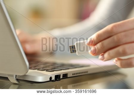 Close Up Of Woman Hands Holding Usb Flash Drive Next To Laptop On A Desk At Home
