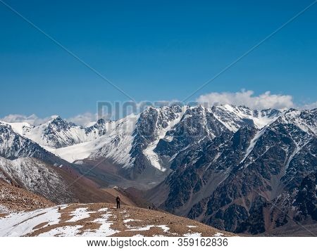 Hiker With A Backpack In The High Snowy Mountains. Great Views Of The Mountain Peaks And The Glacier