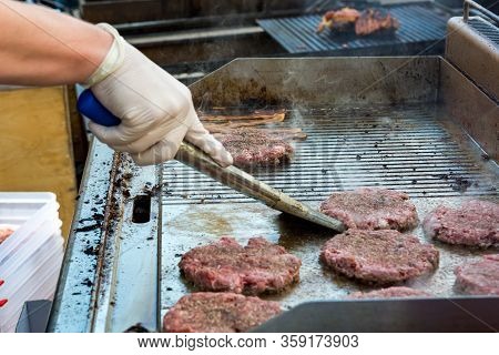 Chef Preparing Delicious Burgers And Flipping Them On Grill.