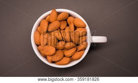 Close Up Of Almonds On A Grey Background In A White Small Cup