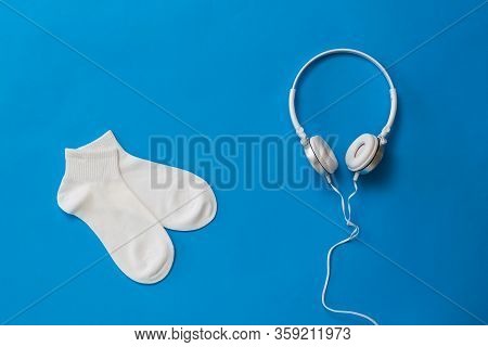 White Sports Socks And White Headphones On A Blue Background. The Color Trend. The Concept Of Music 