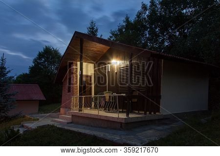 Wooden Bungalows At Night In The Forest. Holiday Apartmens