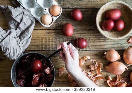 Woman Making Dyed Easter Eggs Painted With Natural Dye Onion On Wooden Background. Process Of Dyeing