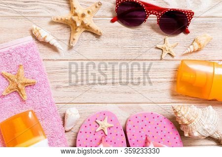 Flip Flops, Straw Hat, Starfish, Sunscreen Bottle, Body Lotion Spray On Wooden Background Top View .