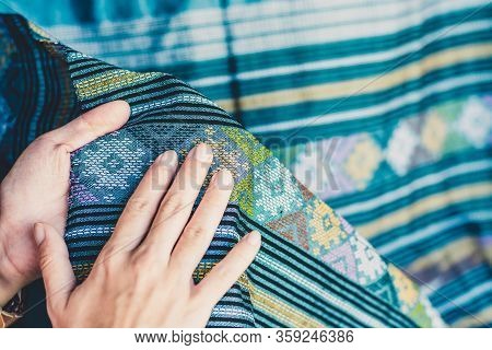 A Young Woman Holds The Traditional Woven Cloth And Rubs Her Hand On The Beautiful Pattern Of The Wo