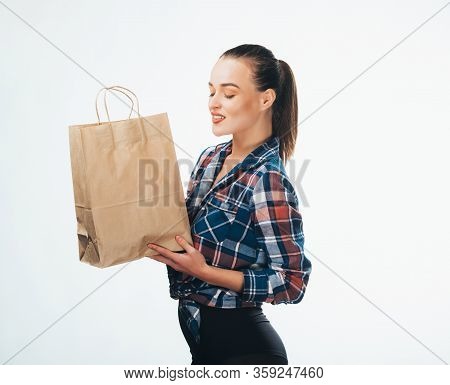Girl With Paper Bags. Consumerism Symbol. Photo From The Side. Brown Paper Bag. Heckered Shirt.