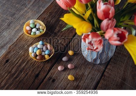 Top View Two Paper Bags With Easter Candies Covered Eggs In Various Pastel Colors Near Vase With Fre