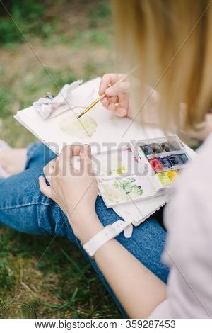 Woman Sits In Pofile And Works On Watercolor Painting.