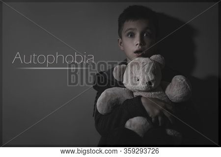 Scared Little With Toy Near Dark Wall. Autophobia