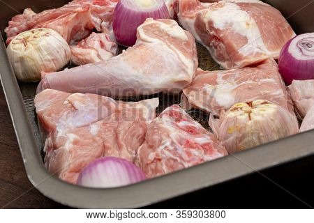 Raw Meat Of Suckling Lamb (suckling Lamb). Prepared On A Roasting Tray (with Garlic And Red Onion).
