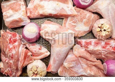 Raw Meat Of Suckling Lamb (suckling Lamb). Prepared On A Roasting Tray (with Garlic And Red Onion).