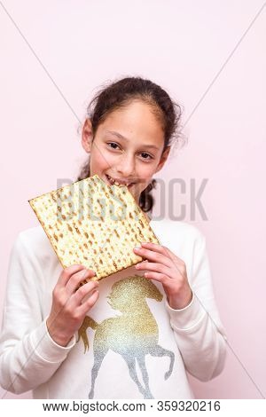Portrait Of The Cute Teenager Girl Holding Matzah. Jewish Child Eating Matzo Unleavened Bread In Jew