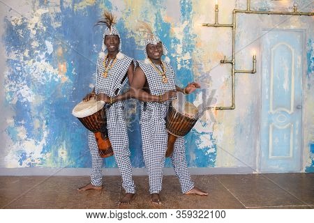 A Group Of People In Traditional African Costumes Playing Jembe Drums