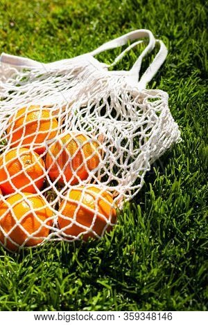 White Cotton Eco String Bag With Oranges On A Grass. Good Idea For A Picnic. Zero And Eco Waste. No 