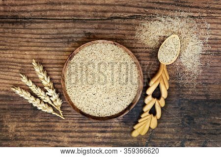 Teff grain health food in a bowl & love spoon with wheat sheath. Highly nutritious rich in fibre, antioxidants, calcium, protein & lowers cholesterol & risk of cardiovascular disease. Flat lay.