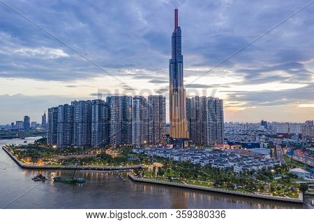 Tall Buildings On Along Riverbank Under Cloudy Sky In Evening