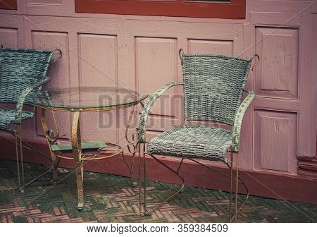 A Vintage Metal Table And 2 Chairs Are On The Outside Of The Coffee Shop, With A Wooden Wall Of Buil