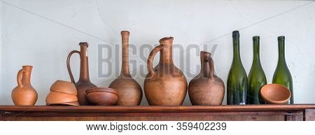A Row Of The Traditional Georgian Wine Jugs, Clay Cups And Bottles On A Wooden Shelf