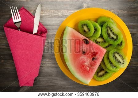 Watermelon And Kiwi Sliced On A Yellow Plate Or A Black Wooden Background .watermelon And Kiw With F