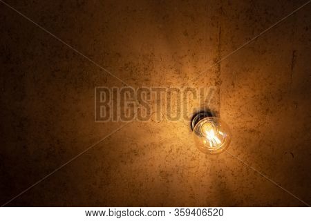 An Electric Lamp Shines On A Brown Background On The Ceiling.
