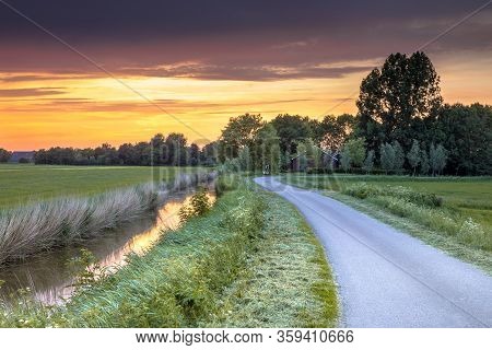 Wide Angle View Of Landscape Over River And Road At Sunset In Flat Agricultural Landscape In Groning