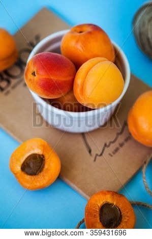 Ripe Juicy Apricots In A White Plate On A Blue Background. Food Photos For Eco-markets, And Agricult