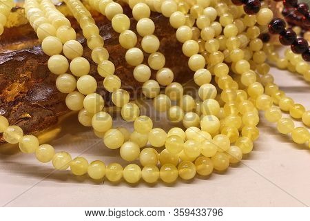 A Lot Of Baltic White Amber Beads Lie On A Large Piece Of Natural Amber. Template For Decorating A J