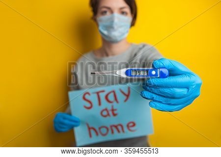 Woman In A Medical Mask With A Temperature. Holding A Thermometer In His Hands. Mild Condition Of A 