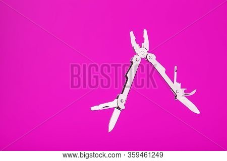 Multitool Is A Multi-functional Tool On A Pink Background. The Concept Of An Open, Flying Multi-tool