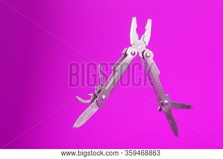 Multitool Is A Multi-functional Tool On A Pink Background. The Concept Of An Open, Flying Multi-tool