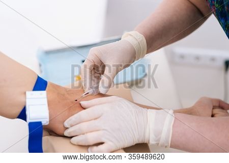 Close-up Pricking Needle Syringe In Blood Sample For Blood Testing. Phlebotomist Technician Drawing 
