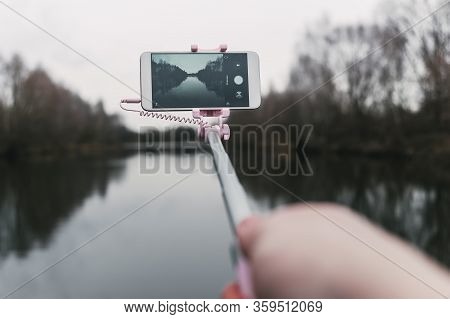 Mock Up White Smartphone In The Hands Of A Man On A Background Of Nature, Water And Trees. Concept O